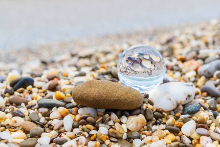 Glass round ball on the beach reflects the sea in summerの写真素材