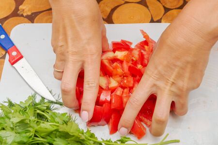 Dicing fresh ripe tomatoes on a white cutting Boardの写真素材