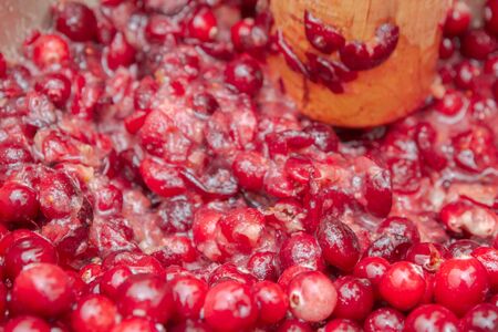 Crush the red cranberry berries with a wooden rolling pinの写真素材