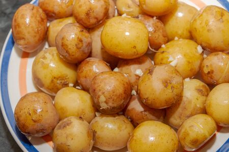 Young boiled potatoes in uniform with garlic and butter lying on a plateの写真素材