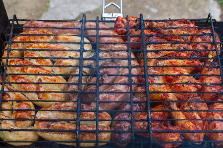Cooking grilled meat wings and sausages on the grill