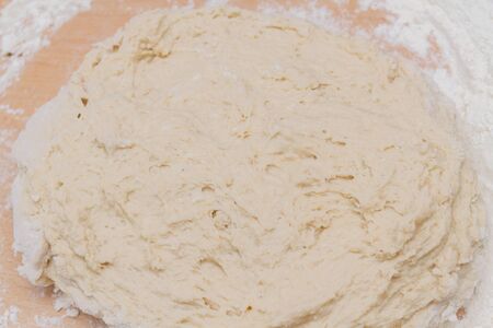 Kneading dough with flour on a wooden table at home