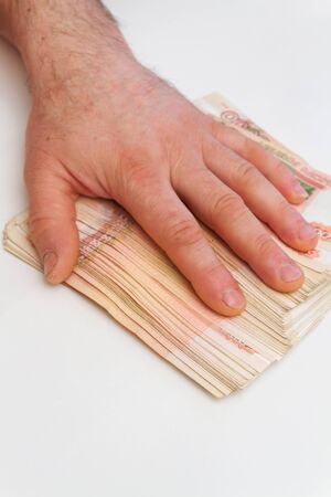A man's hand counts and shifts a large number of five thousand rubles bills into a stack