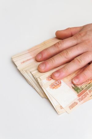 A man's hand counts and shifts a large number of five thousand rubles bills into a stack