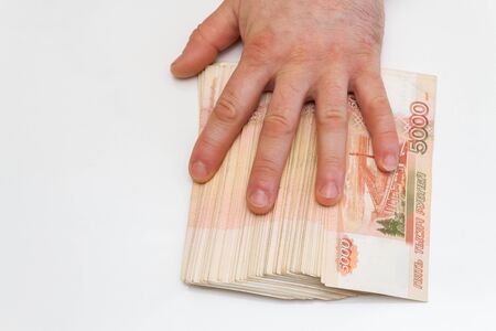 A man's hand counts and shifts a large number of five thousand rubles bills into a stack