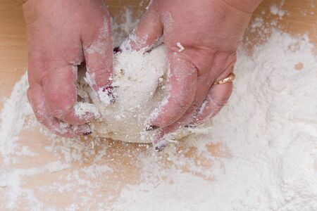 Kneading dough with flour on a wooden table at home