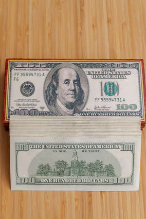 A large wad of American dollars is lying next to a wooden boxのeditorial素材