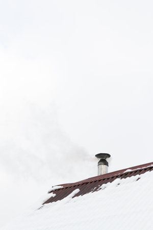 The chimney smokes on the roof of the houseの写真素材