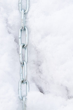 A metal chain lies on the snow in winterの写真素材