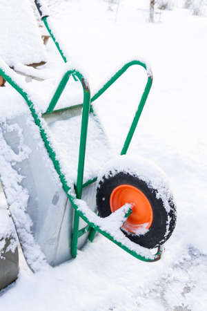 Metal garden wheelbarrow in the snow in winterの写真素材