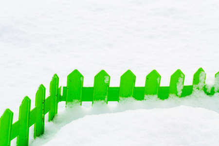 Green plastic fence in the snow in the garden in winterの写真素材