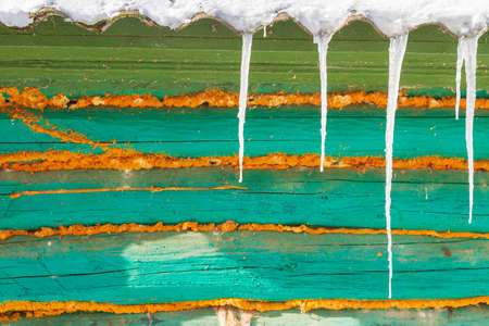 Icicles hang from the roof of an old wooden houseの写真素材