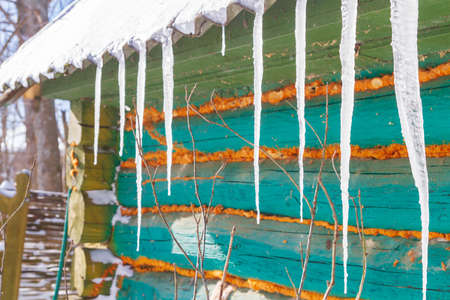 Icicles hang from the roof of an old wooden houseの写真素材