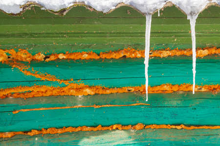 Icicles hang from the roof of an old wooden houseの写真素材