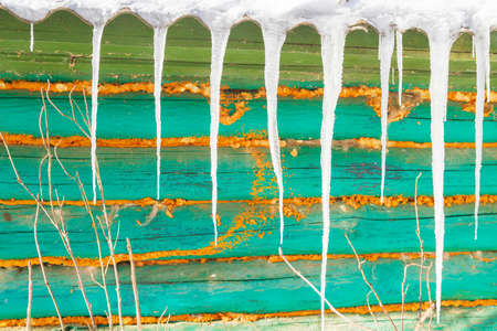 Icicles hang from the roof of an old wooden houseの写真素材