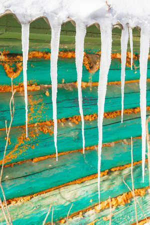 Icicles hang from the roof of an old wooden houseの写真素材
