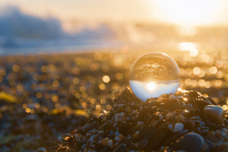 Glass round ball on the beach reflects the sea in summer at sunsetの写真素材