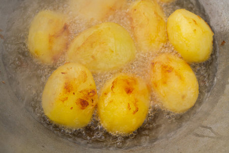 Golden potatoes are fried in boiling oil in a cauldronの写真素材