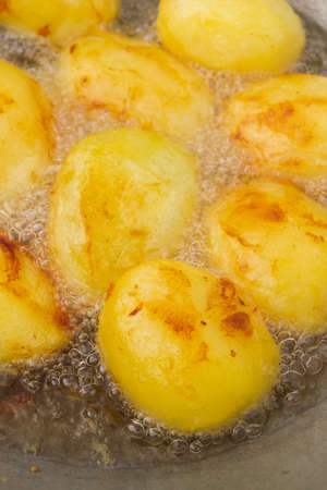 Golden potatoes are fried in boiling oil in a cauldronの写真素材