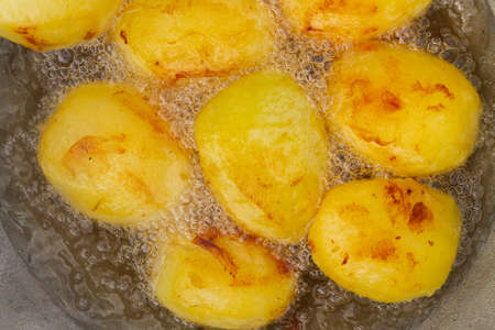 Golden potatoes are fried in boiling oil in a cauldronの写真素材