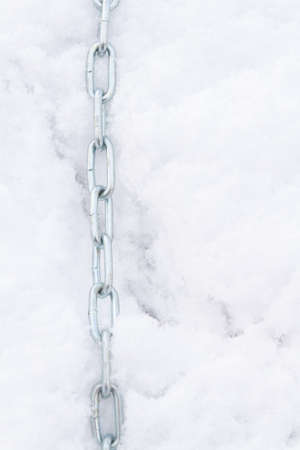A metal chain lies on the snow in winterの写真素材