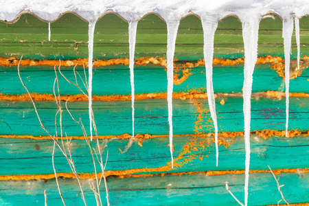 Icicles hang from the roof of an old wooden houseの写真素材