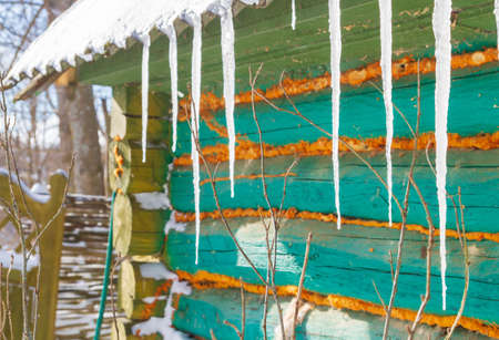 Icicles hang from the roof of an old wooden houseの写真素材