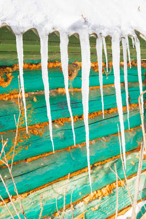 Icicles hang from the roof of an old wooden houseの写真素材