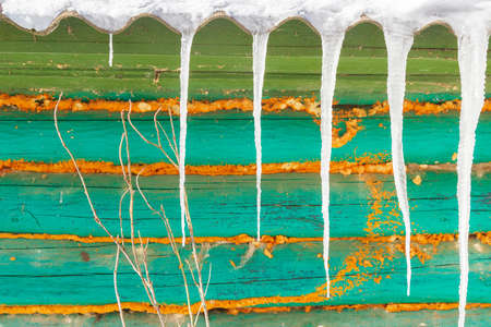 Icicles hang from the roof of an old wooden houseの写真素材