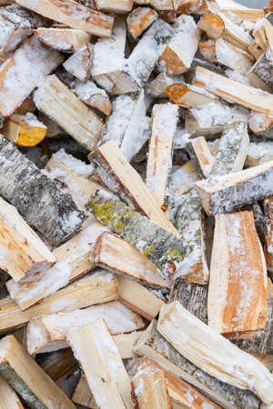 Chopped birch firewood lies in a heap on the snow in winterの写真素材