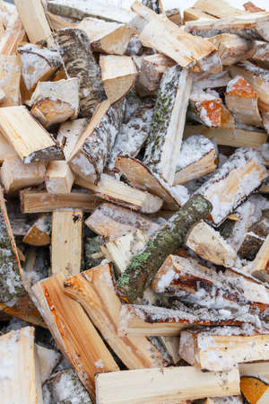 Chopped birch firewood lies in a heap on the snow in winterの写真素材