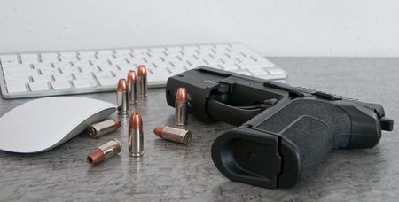 SIG PRO pistole with bullets on the table near mouse and keyboardの写真素材