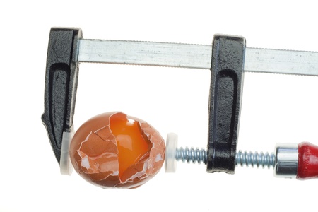 Pressure stress concept with broken egg and clamp isolated on whiteの写真素材