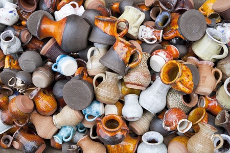 Background from small ceramic multi-colored jugs and cups. Mass production, selective focus