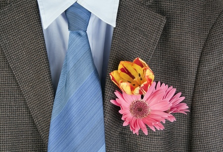Flowers  in a pocket of an old shabby brown tweed jacket and a dark blue tie, background. Concept of the provincial groomの写真素材