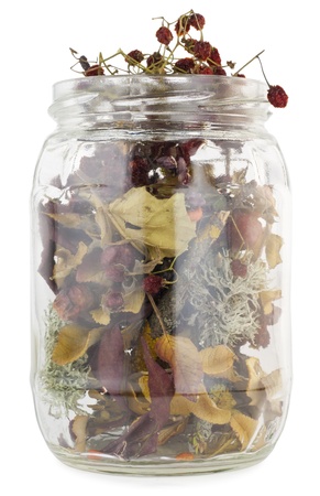 Glass vessel with the dried up medical (magic) plants and berries macro. Isolated on whiteの写真素材