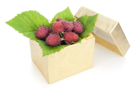 Sweet raspberry lies in a small gold mass production  box isolated. Useful and tasty gift concept