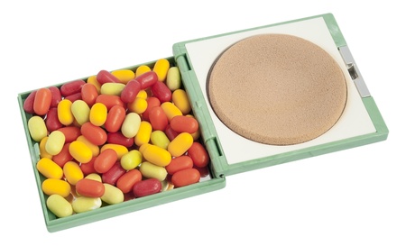 Multi-coloured tablets  pills  lie in a female powder box. Isolated with patchの写真素材