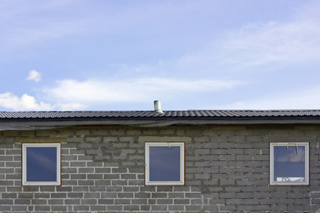 Three plastic windows in long brick barracks against the skyのeditorial素材