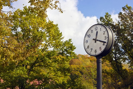 Autumn Time is eighteen minutes in the afternoon concept. Big clock in autumn city park landscapeの写真素材