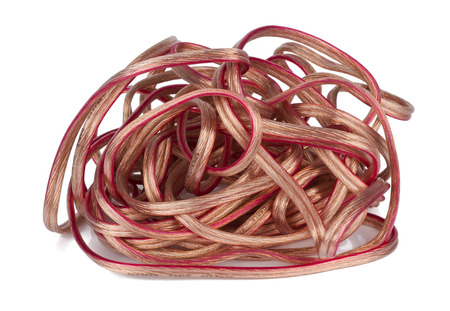 Chaos of the high end copper speaker cable in thick plastic isolation lies on a white table....
