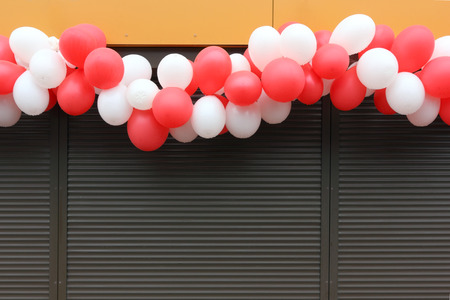 The garland of white and red balloons hangs over the window closed by brown blinds.Rainy dayの写真素材