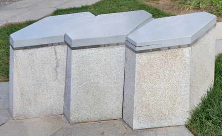 The modern city park bench is made of hexagonal pieces of granite and woodの写真素材