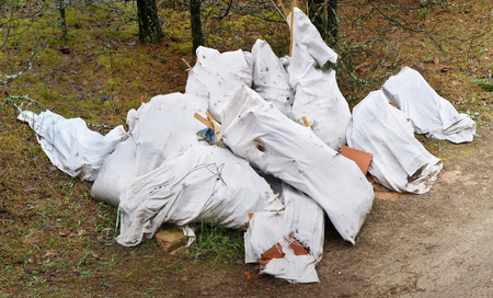 Barbarous attitude to ecology and nature concept. Bags with construction debris lie on a forest gladeの写真素材