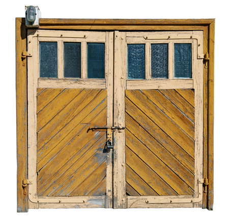 Vintage yellow aged cracked wooden garage doors with glass windows. Isolated on white with patch. Sunny day outdoor shotの写真素材
