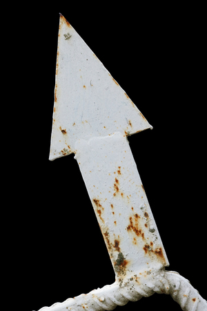 Decorative element of a rural fence - iron rusty white arrow. Isolated on black backgroun