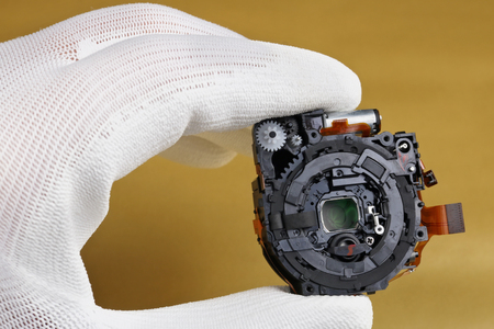 A technician controls the quality of a modern lens assy  for a photo camera. Masss production.  Modern technology  macro concept.の写真素材