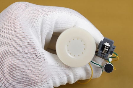 A technician controls the quality of a mini speaker an microphone  for phone handset. Mass production. Modern technology  macro concept.の写真素材