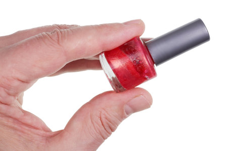 An elderly man holds in his hand a bottle of red nail polish. Isolated on white studio macro