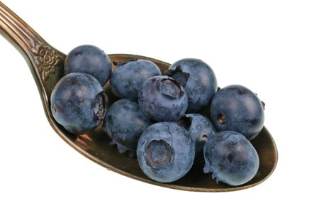 In the old golden spoon there is a small pile of food - ripe blueberries  garden fruits. Isolated on...